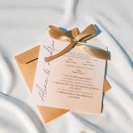 Invitație nuntă elegantă crem cu fundiță aurie și plic kraft natural
